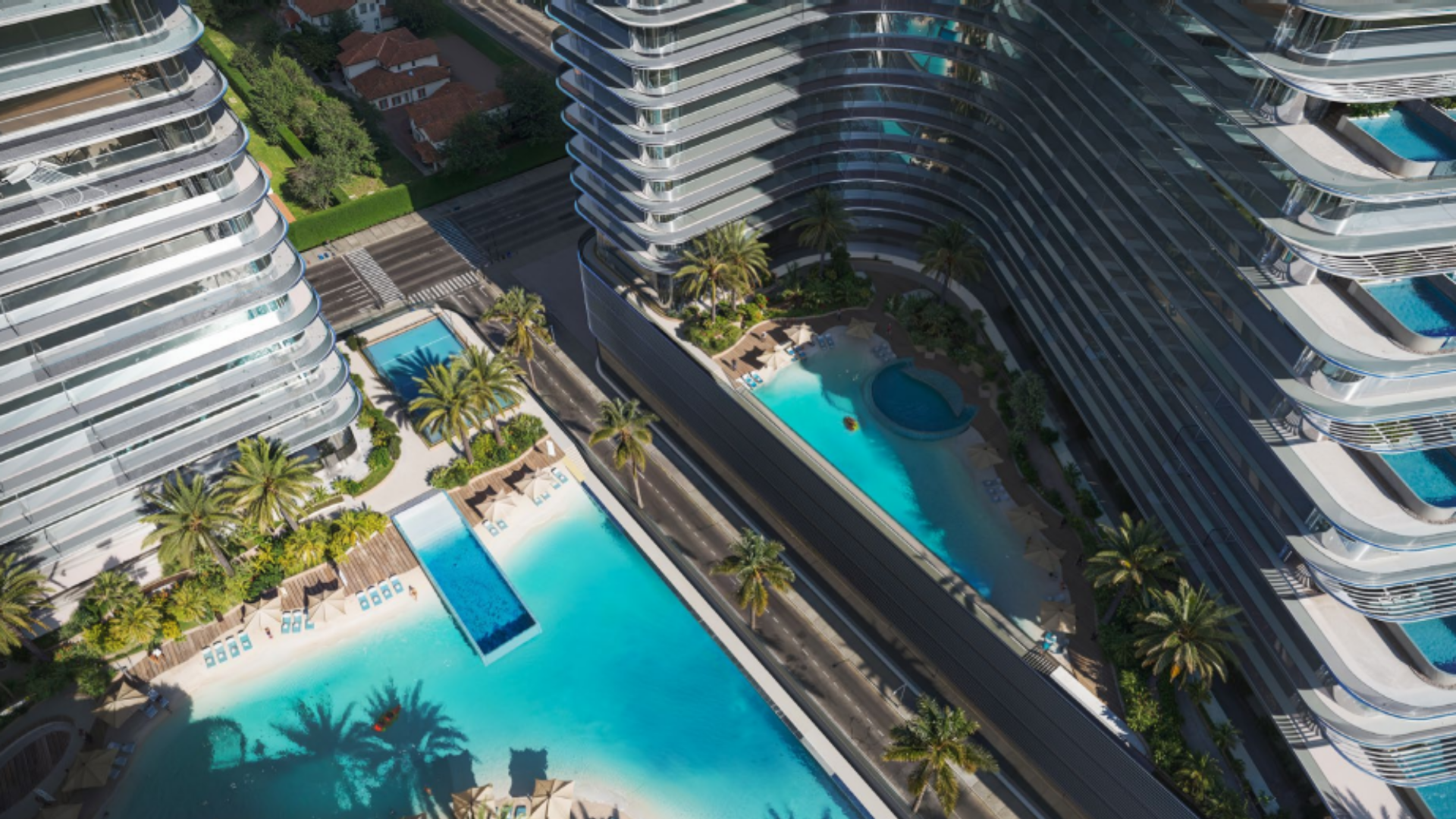 Aerial view of luxury pools surrounded by high-rise buildings and palm trees