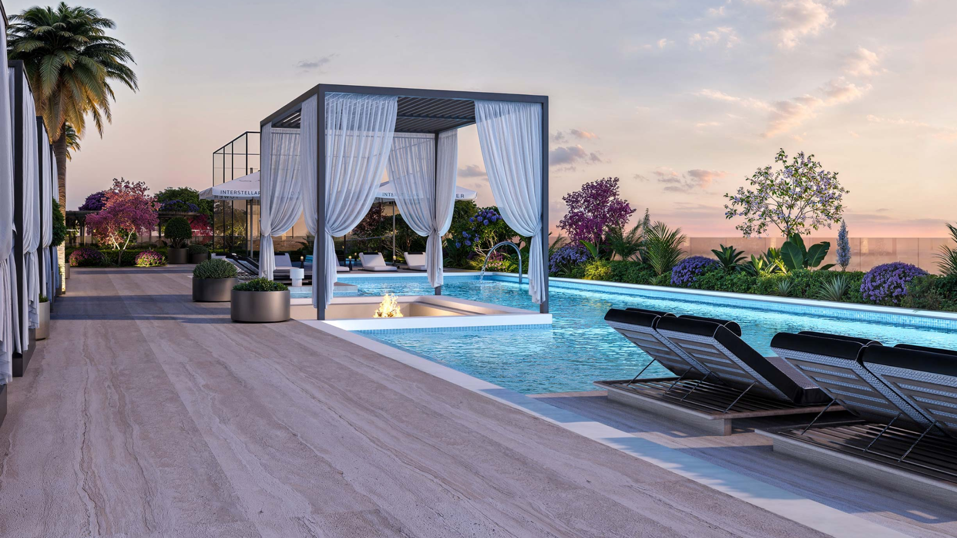 Elegant rooftop pool with cabanas, lounge chairs, and fire feature at sunset