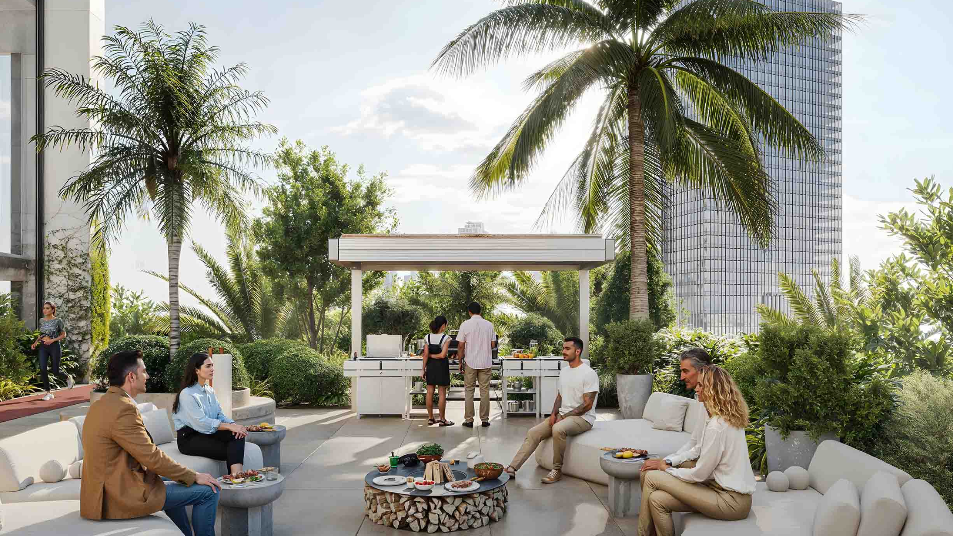 Spacious outdoor lounge area with people socializing, barbecue station, and palm trees.