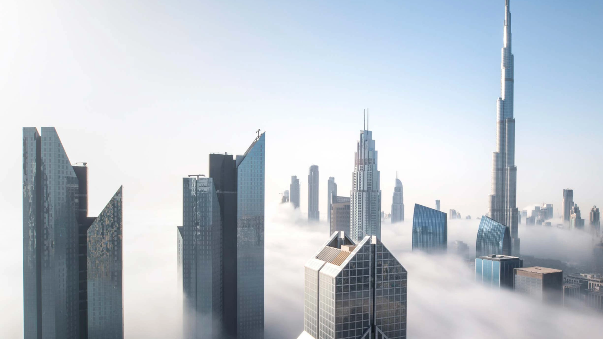 The iconic Dubai skyline with the Burj Khalifa visible above a blanket of fog