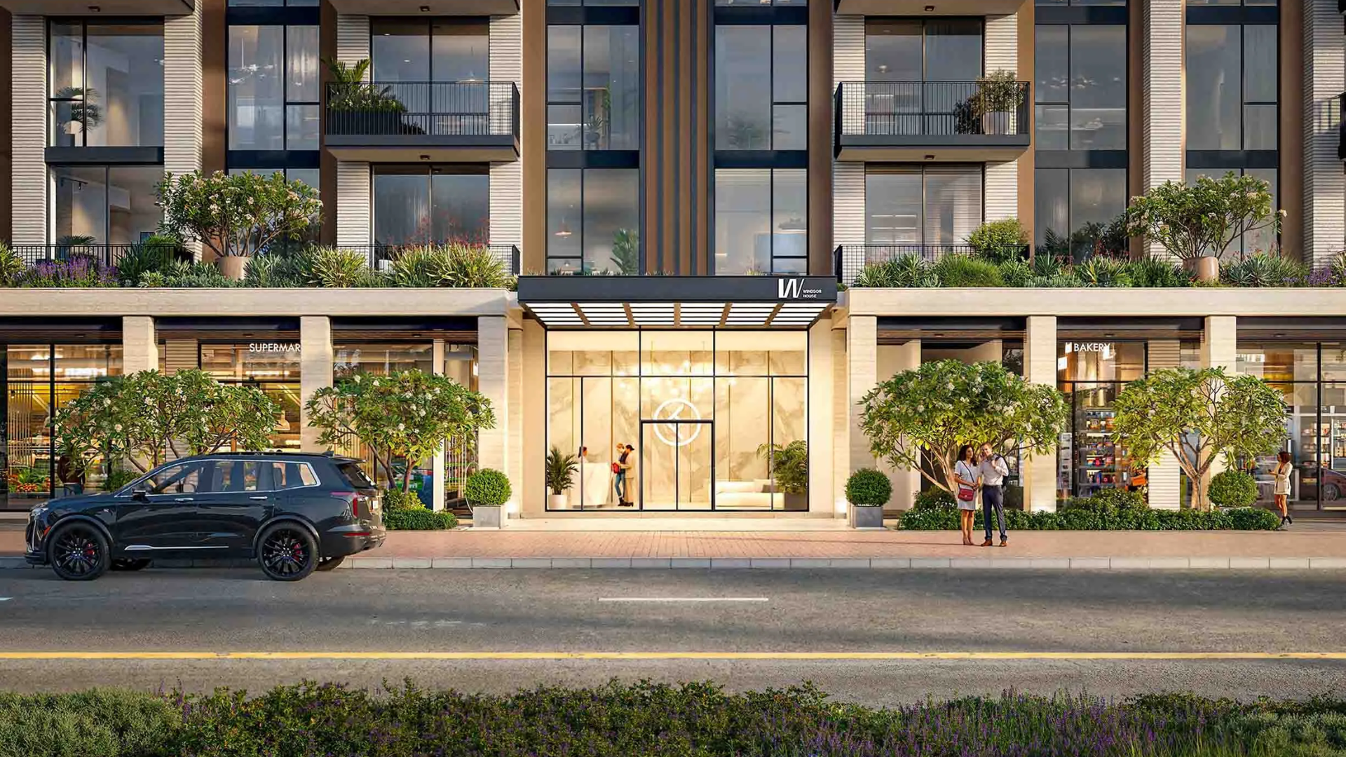 Entrance of a modern residential building with landscaped greenery and retail shops