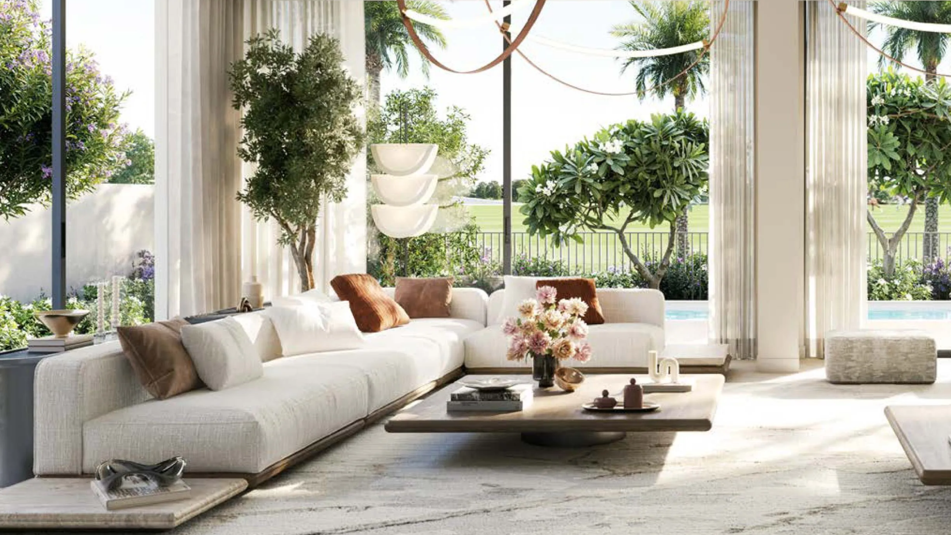 A bright living room in a Chevalia Estate 2 villa with floor-to-ceiling windows and a view of the pool and golf course.