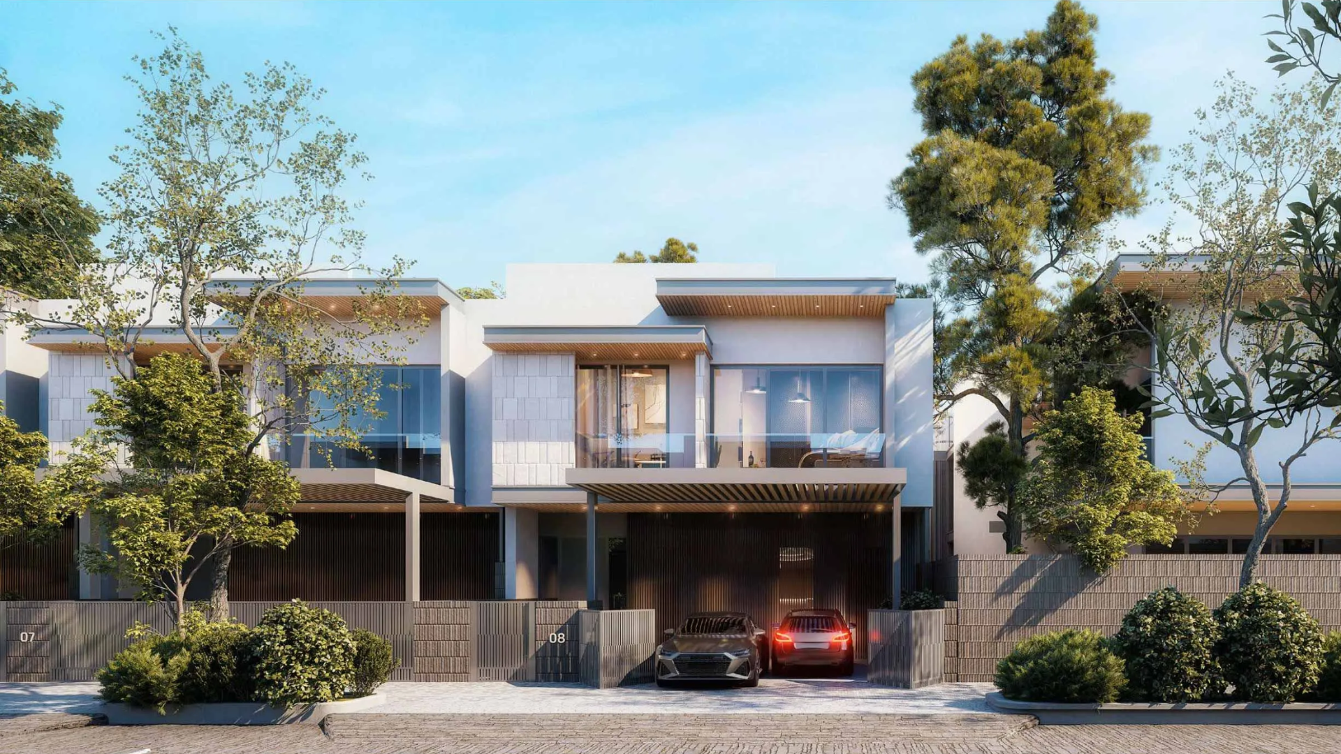 Row of modern villas with integrated carports and lush landscaping along a street.