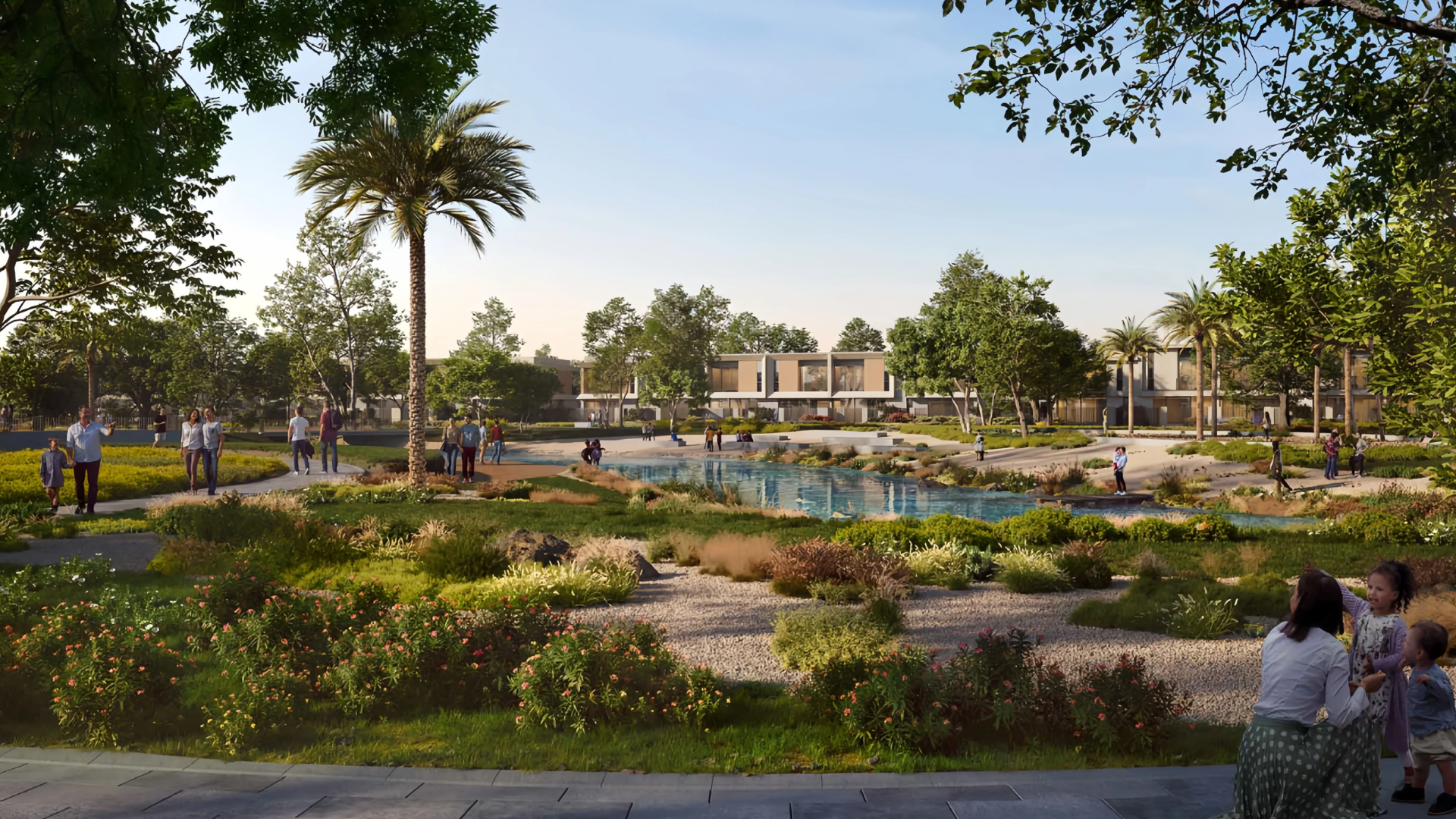 Outdoor recreational area with a central pond, playground, and people strolling through gardens.