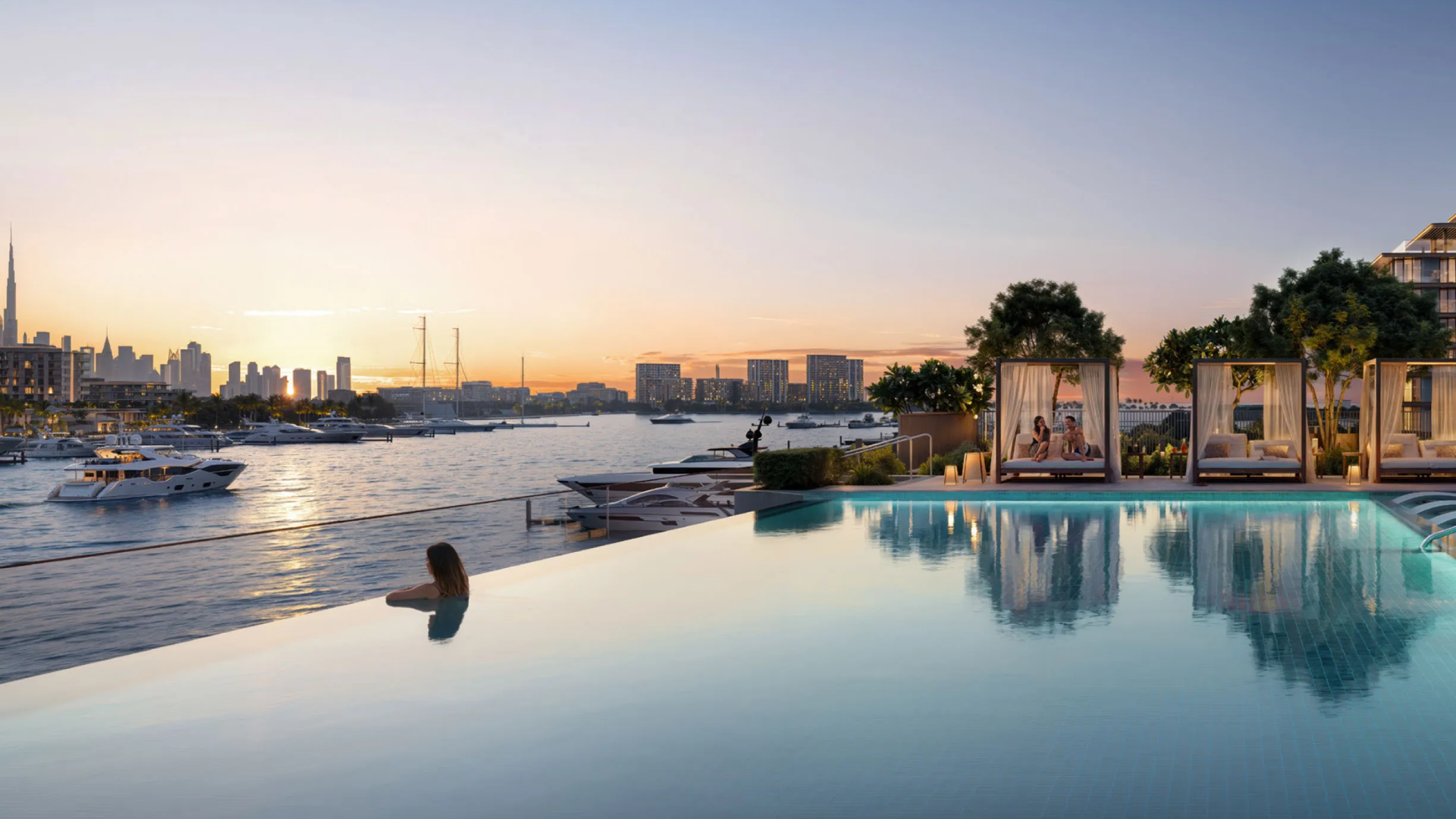 Infinity pool overlooking a marina with yachts and a panoramic city skyline view at sunset.