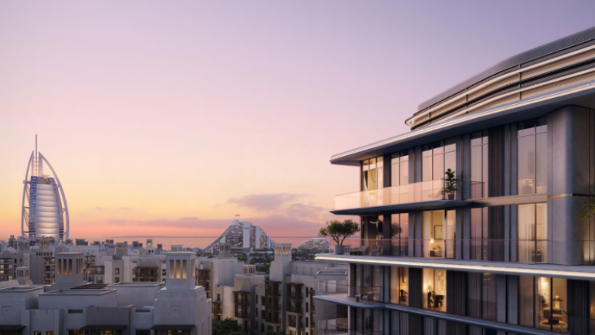 Modern luxury residential building with spacious balconies overlooking a city skyline at sunset.