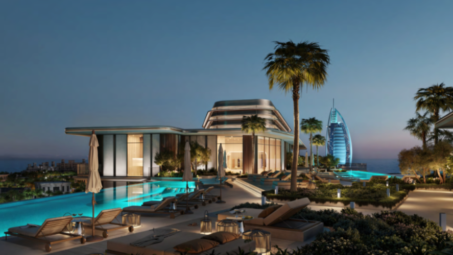 Rooftop infinity pool and lounge deck at twilight with a view of the ocean and the Burj Al Arab hotel.