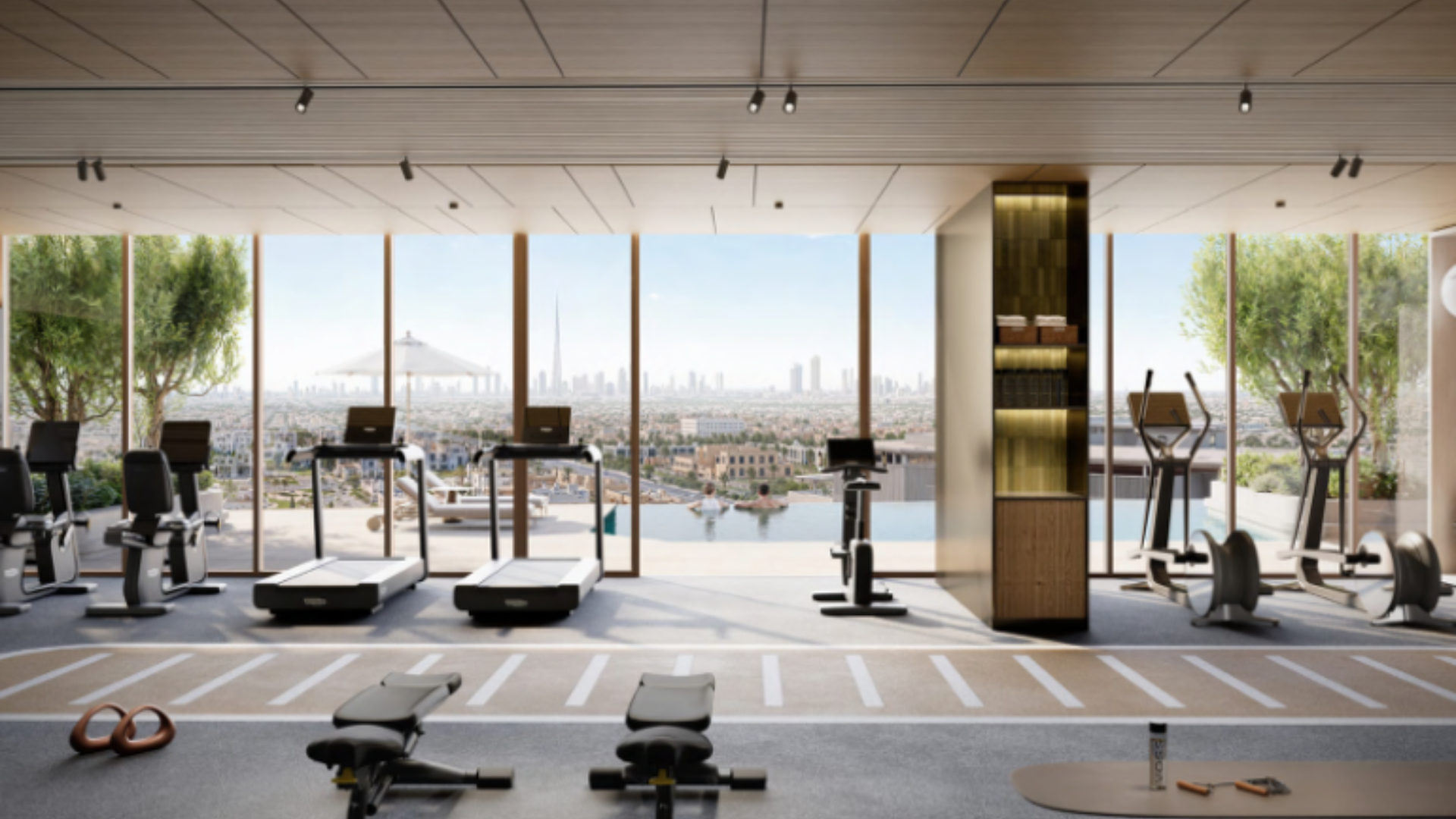 A modern gymnasium with cardio equipment and floor-to-ceiling windows overlooking a swimming pool and the city skyline.