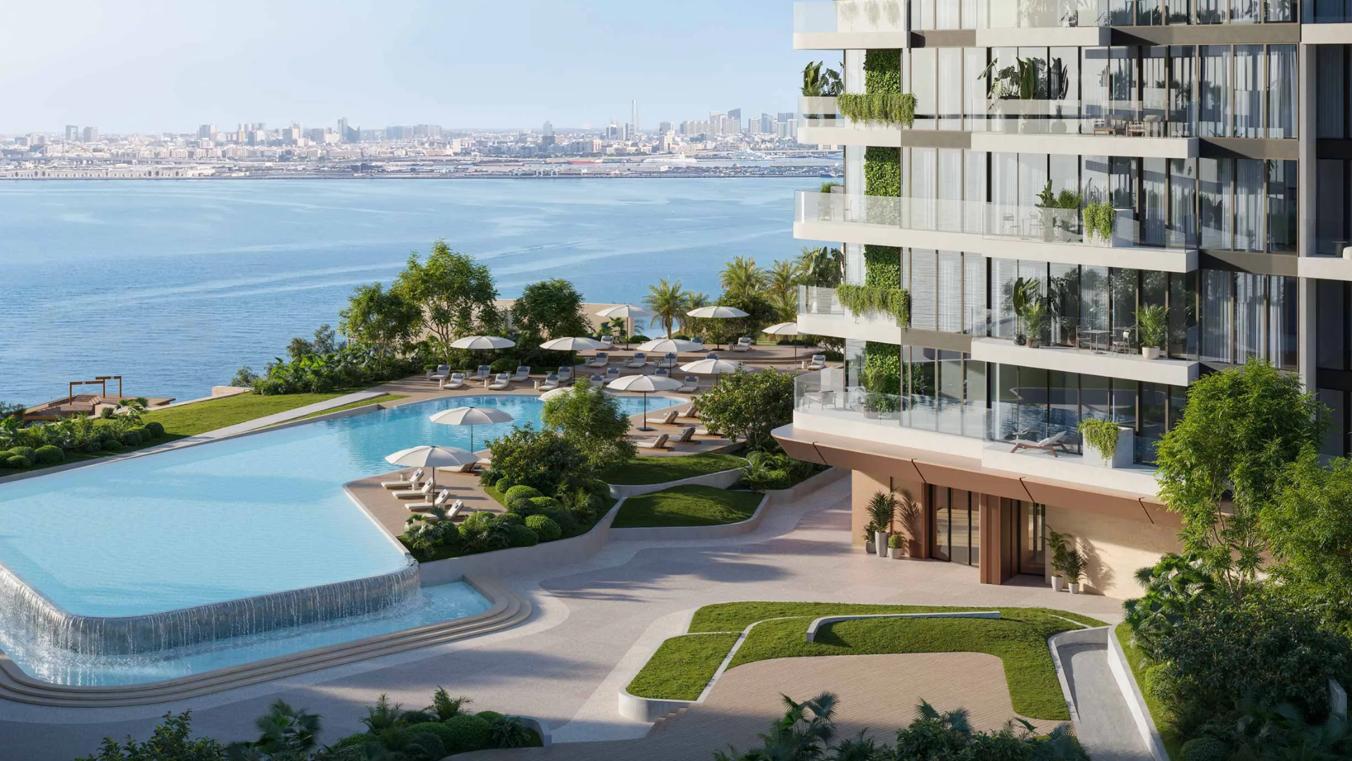 Infinity-edge pool with a waterfall, overlooking the sea and city skyline, beside a modern glass high-rise.