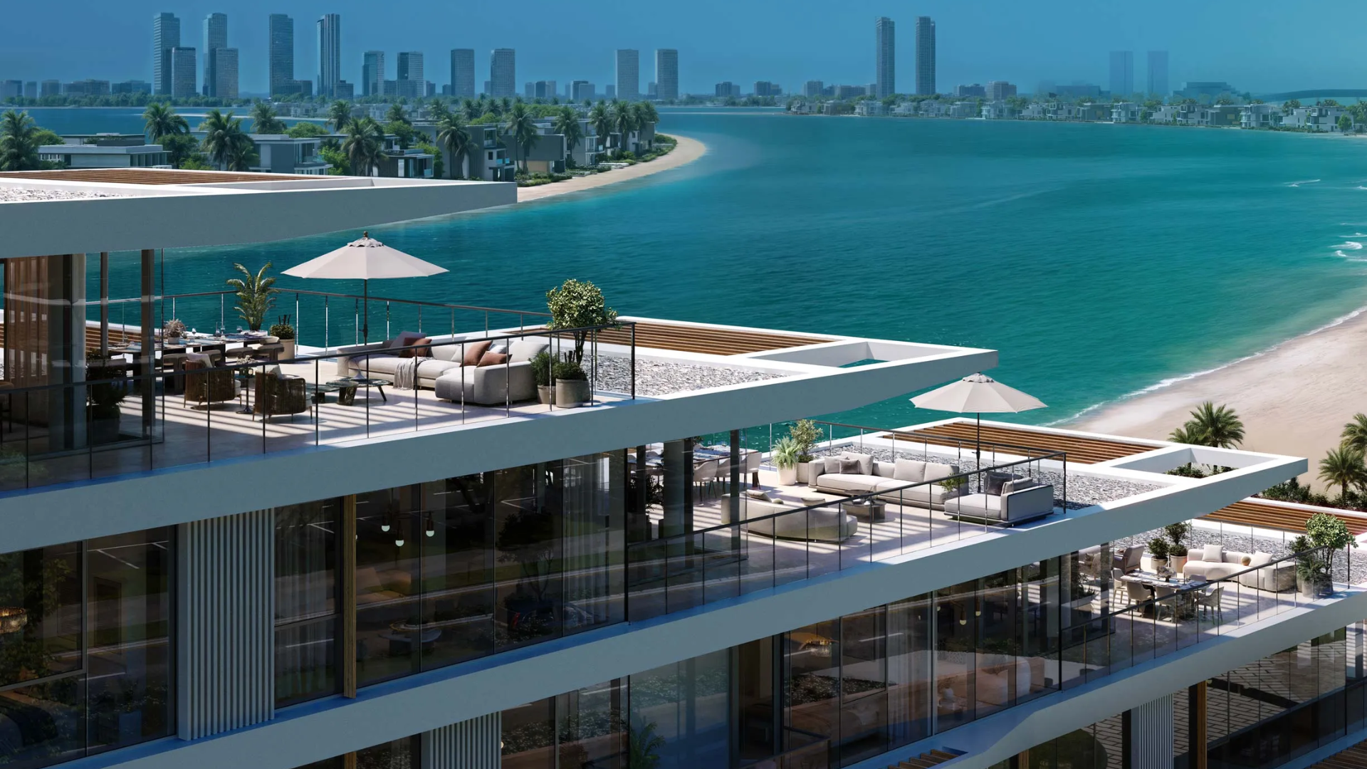 Residential buildings with tiered balconies viewed from a serene, crescent-shaped beach and clear blue water.