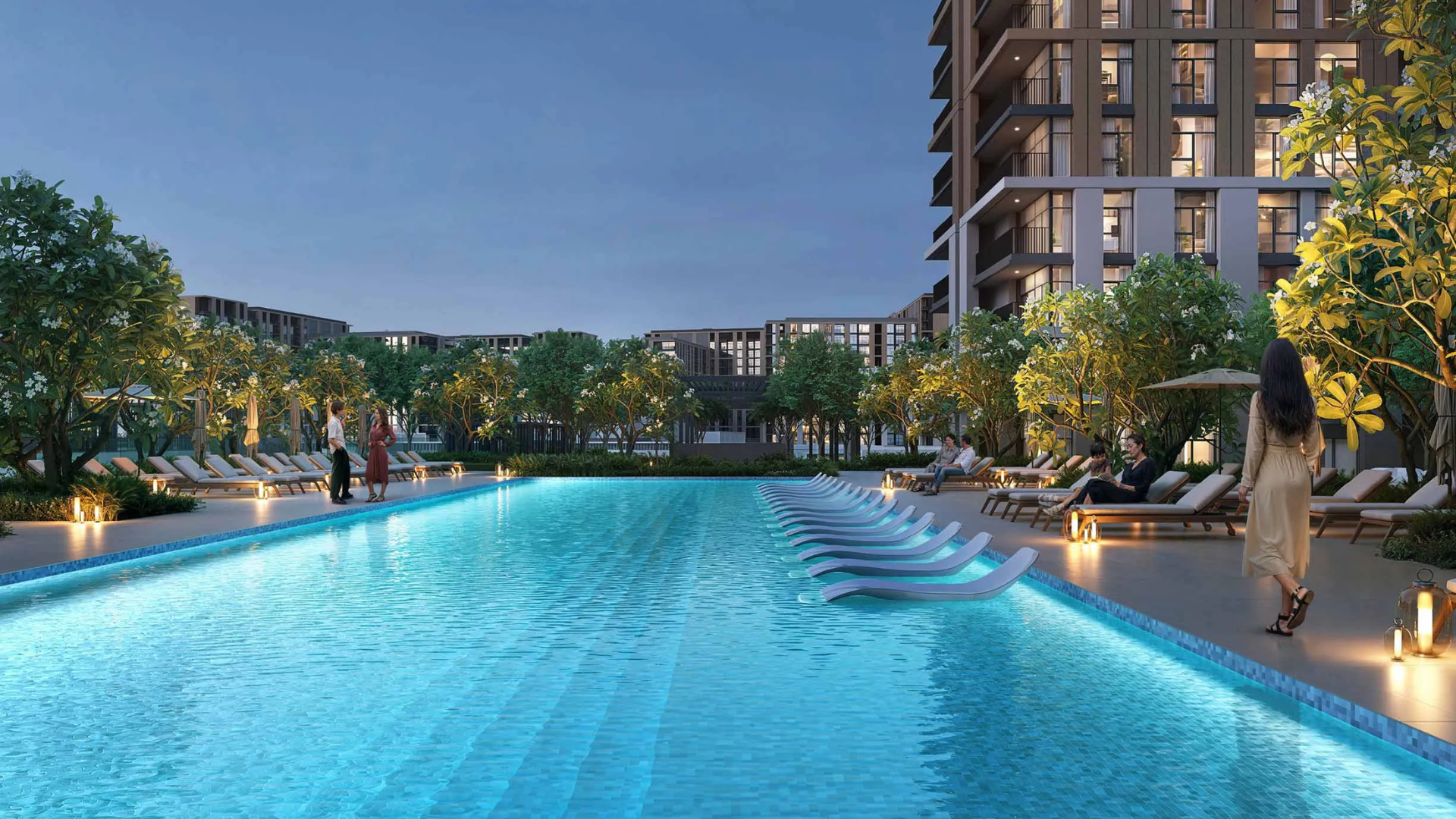 The long, resort-style swimming pool amenity designed by Emaar , featuring submerged lounge chairs and ambient lighting at dusk.
