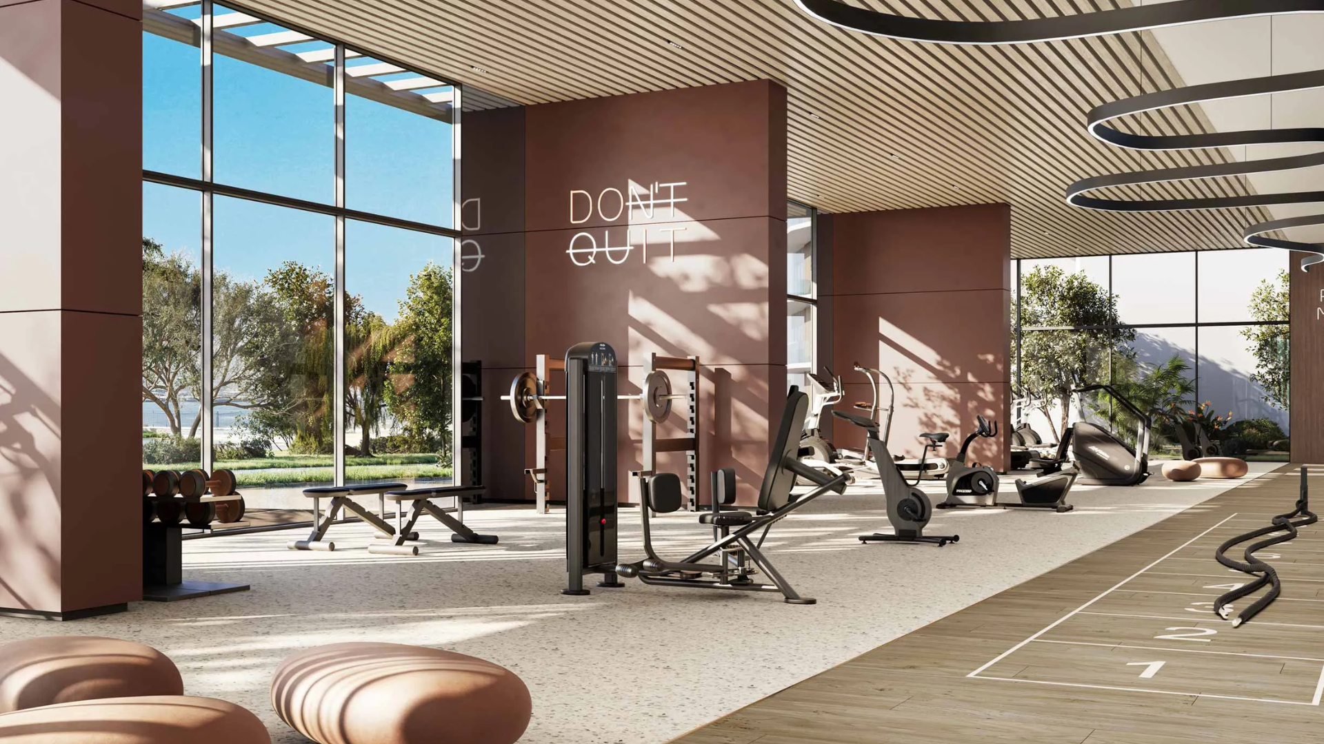 Modern fitness center designed by Meraas with high ceilings, large windows, and motivational text on the wall.